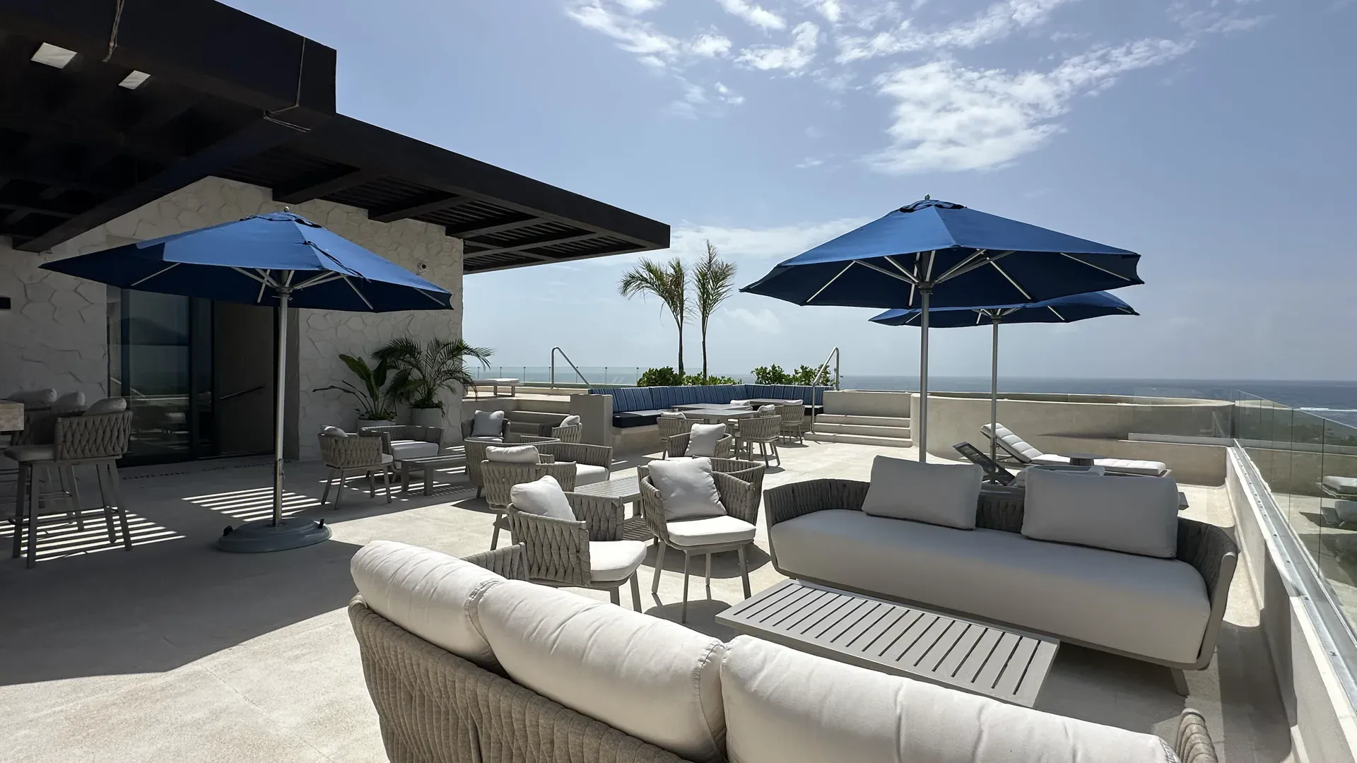 Terraza lounge de Sole BLU con salas exteriores, sombrillas azules y vista al mar